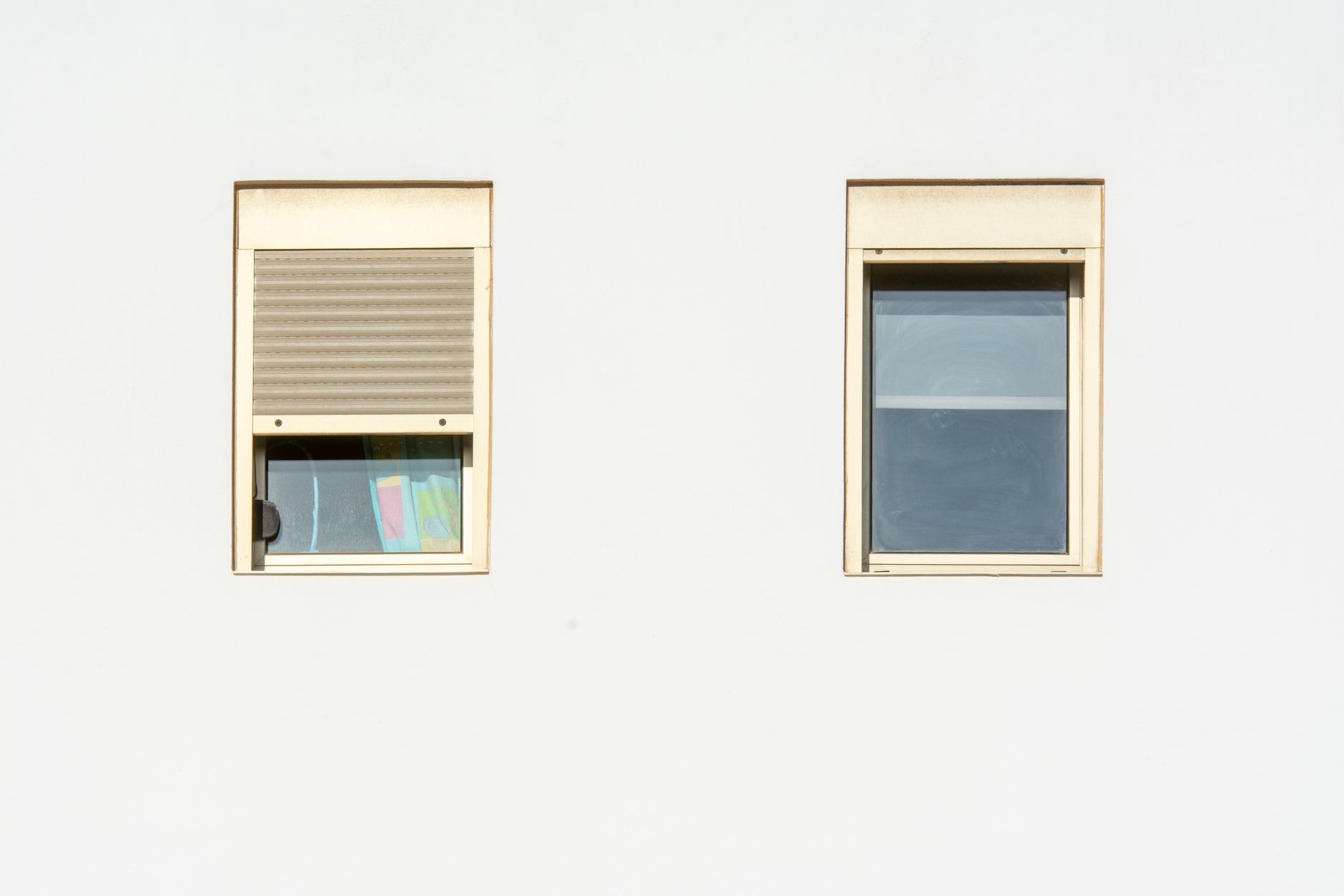 A minimalistic facade featuring two modern windows with shutters in a bright, contemporary style in Carlsbad, CA