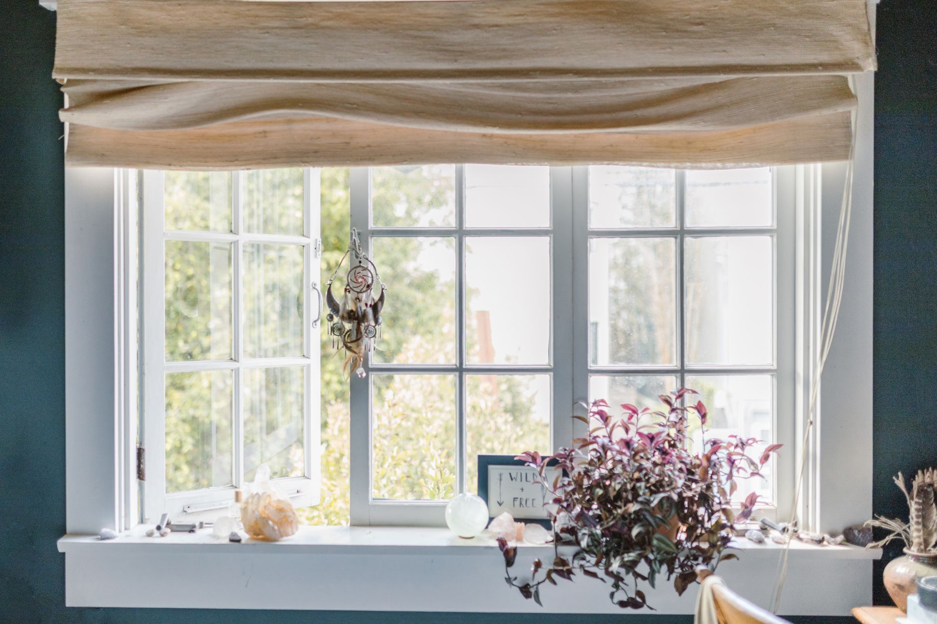 A serene indoor window scene with a dreamcatcher, crystals, and potted plant in Carlsbad, CA